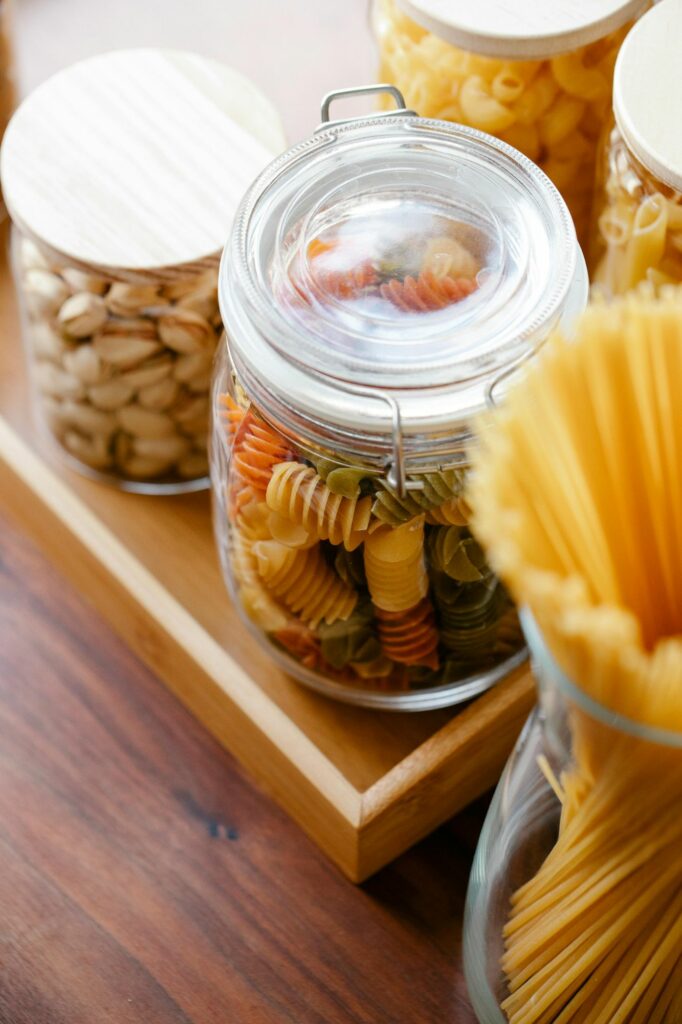 frascos de vidro com massa e alimentos organizados na despensa
